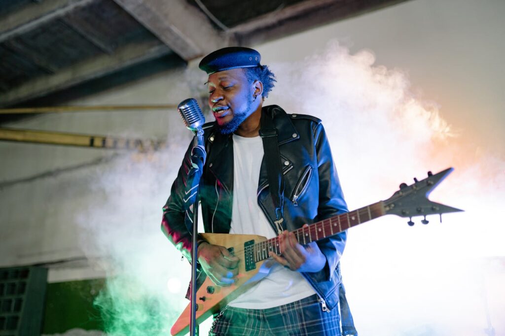 Musician rocking an electric guitar on stage with dramatic lighting and smoke effects.